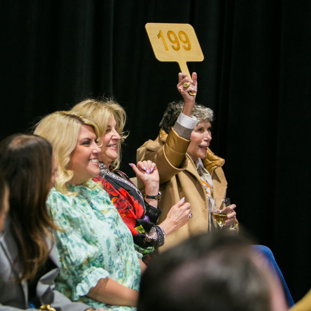woman raising auction paddle