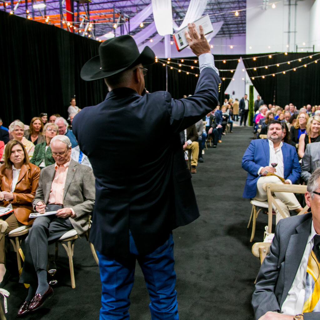 Auctioneer wearing a cowboy hat with his back to the camera