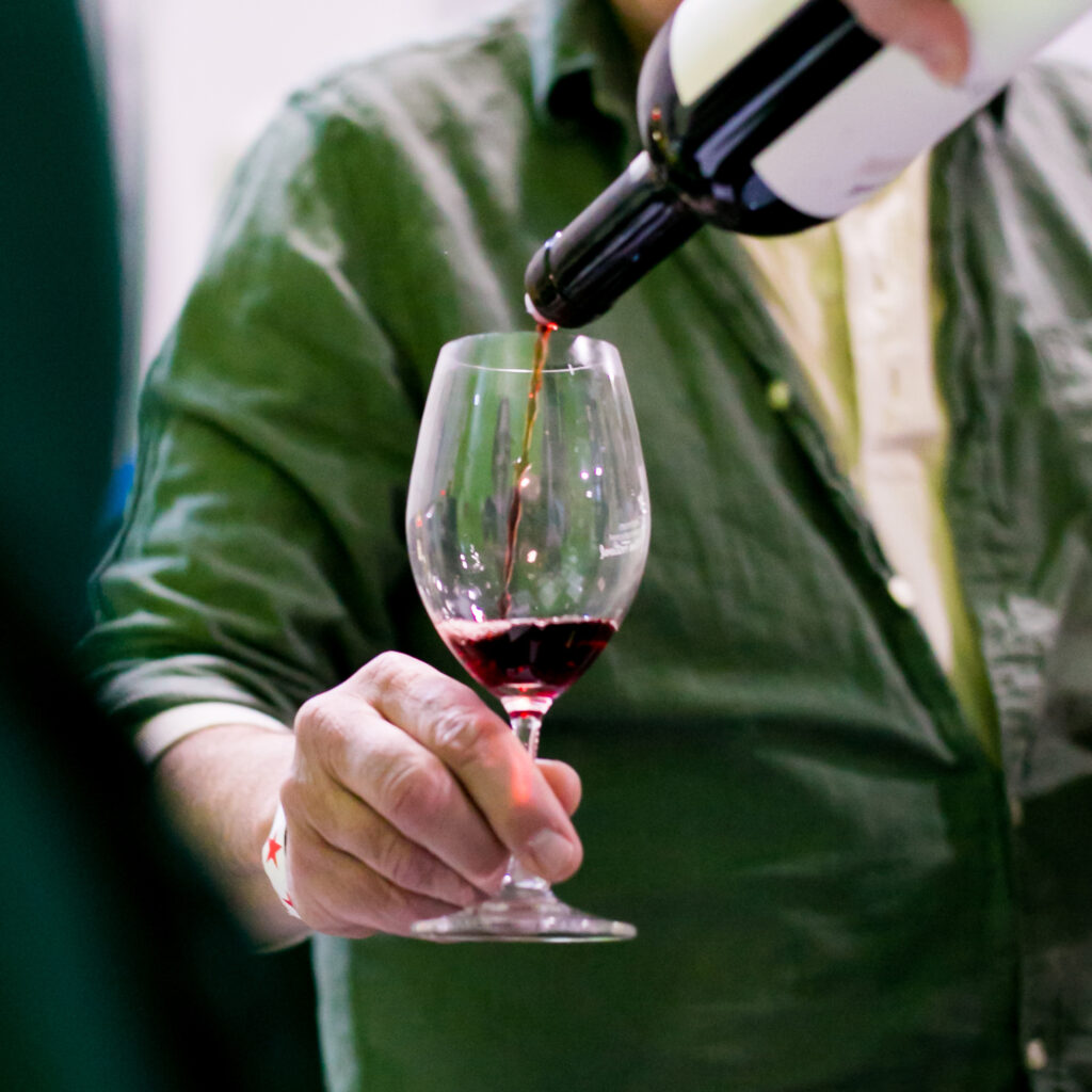 red wine being poured into a glass held by a man